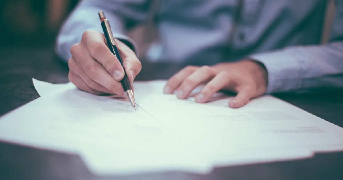 Person signing business documents at a desk, used for Shopify legal and store details

---

# content